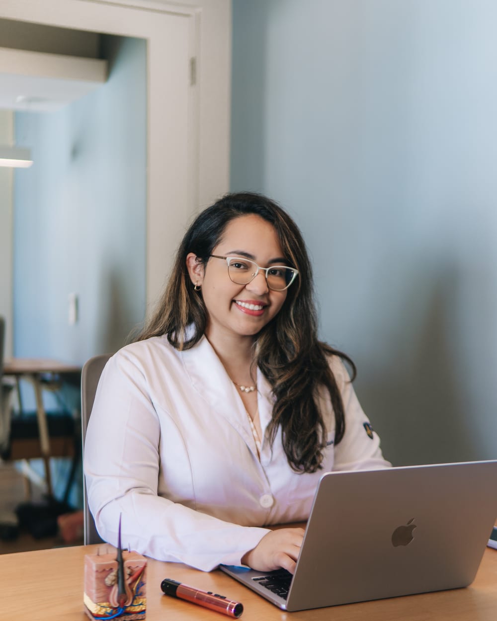 Dra. Luciana Monteiro no consultório, ao computador